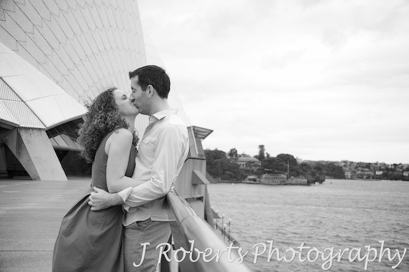 Couple kissing against a railing at Sydney Opera House - engagement photography sydney